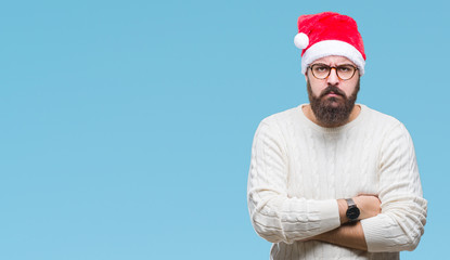 Young caucasian man wearing christmas hat and glasses over isolated background skeptic and nervous, disapproving expression on face with crossed arms. Negative person.