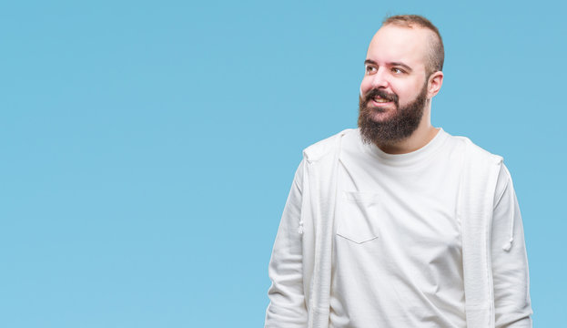 Young caucasian hipster man wearing sport clothes over isolated background looking away to side with smile on face, natural expression. Laughing confident.