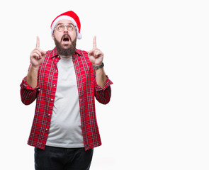 Young caucasian man wearing christmas hat over isolated background amazed and surprised looking up...