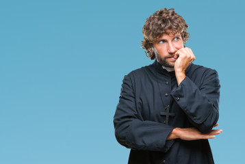 Handsome hispanic catholic priest man over isolated background looking stressed and nervous with...