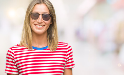 Young beautiful woman wearing sunglasses over isolated background with a happy and cool smile on face. Lucky person.