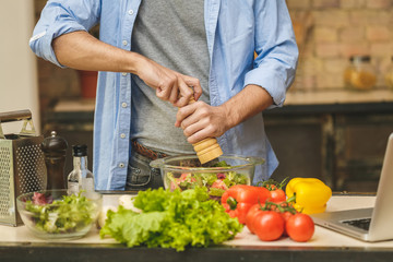 Close-up of young man preparing delicious and healthy food in the home kitchen on a sunny day.