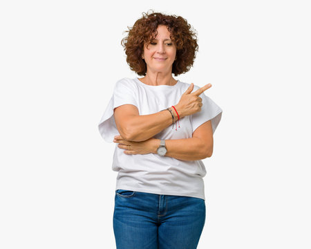 Beautiful middle ager senior woman wearing white t-shirt over isolated background Pointing with hand finger to the side showing advertisement, serious and calm face