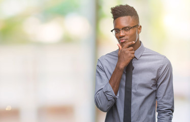 Young african american business man over isolated background looking confident at the camera with smile with crossed arms and hand raised on chin. Thinking positive.