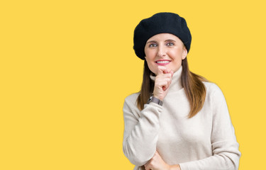 Middle age mature woman wearing winter sweater and beret over isolated background looking confident at the camera with smile with crossed arms and hand raised on chin. Thinking positive.