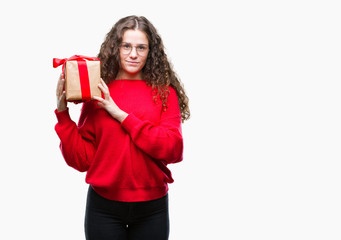 Young brunette girl holding a gift over isolated background with a confident expression on smart face thinking serious