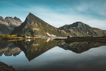 Naklejka na ściany i meble The stunning maointain near Fredvang in Lofoten Islands, Norway seen from a drone aerial with reflection on a clear day with blue sky.