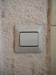 Old and filthly typical german light switch on wall with dirty Raufasertapete