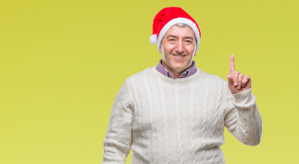 Fototapeta na wymiar Handsome senior man wearing christmas hat over isolated background showing and pointing up with finger number one while smiling confident and happy.