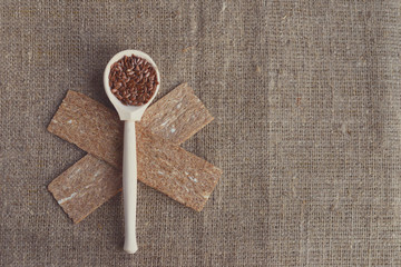 wooden spoon with flax seeds and dietary crispbread on canvas