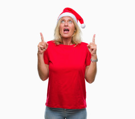 Middle age blonde woman wearing christmas hat over isolated background amazed and surprised looking...