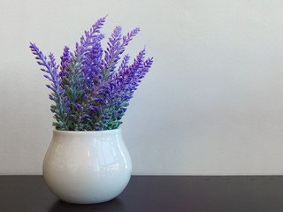 Lavender flowers in white vase with copy space wall background.