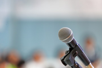 Standing microphone for speaker's speech in the seminar room with audience in the background 