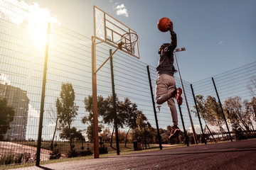Perfect hit. Handsome Afro American man holding a ball while throwing it into the basket