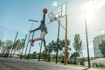 Into the basket. Low angle of a nice young man jumping up while throwing the ball in the basket © zinkevych