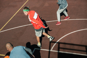 My team. Nice young man looking at his team members while standing on the basketball ground