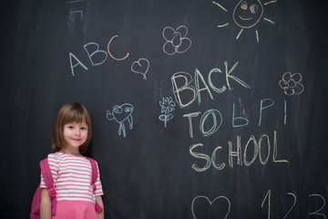 school girl child with backpack writing  chalkboard