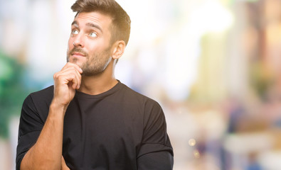 Young handsome man over isolated background with hand on chin thinking about question, pensive expression. Smiling with thoughtful face. Doubt concept.