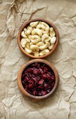 Bowls of organic cranberries and cashews on brown paper.