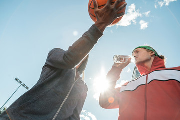 Water balance. Low angle of a pleasant nice man drinking water while talking to his friend © zinkevych