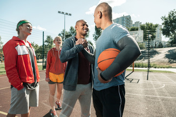 Ready to train. Joyful happy man smiling while greeting his basketball coach