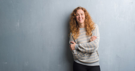 Fototapeta premium Young redhead woman over grey grunge wall happy face smiling with crossed arms looking at the camera. Positive person.
