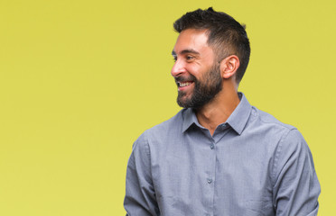 Adult hispanic man over isolated background looking away to side with smile on face, natural expression. Laughing confident.