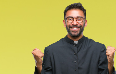 Adult hispanic catholic priest man over isolated background celebrating surprised and amazed for...