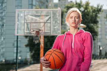 Sport for women. Attractive sportive woman looking at you while standing with a ball in her hands