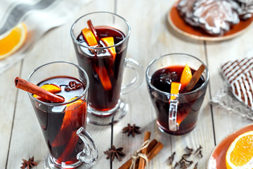 Mulled wine with spices and cookie on wooden background