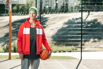 Obraz premium Time for sport. Pleasant nice man standing on the sportsground while coming to play basketball