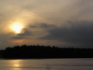 the sun in the clouds above the lake