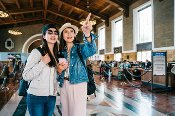 joyful female travelers pointing to the sign