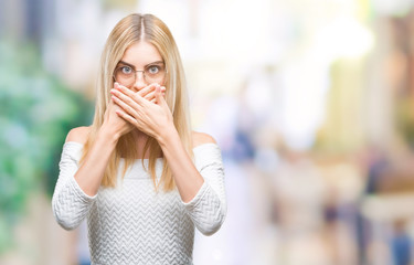 Young beautiful blonde woman wearing glasses over isolated background shocked covering mouth with hands for mistake. Secret concept.