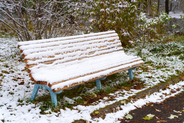 Autumn Scenery: Old Garden Bench in Late Fall Covered by First Snow. Shoot in October - 230345685