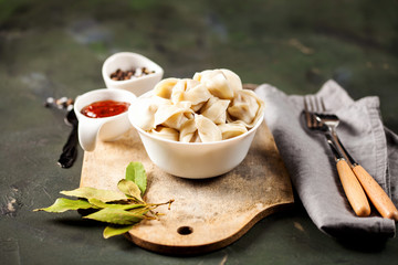 Traditional russian pelmeni, ravioli, dumplings with meat on concrete background. Russian food and russian kitchen concept. Selective focus