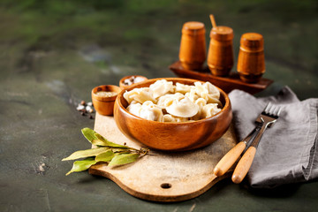 Traditional russian pelmeni, ravioli, dumplings with meat on concrete background. Russian food and russian kitchen concept. Selective focus