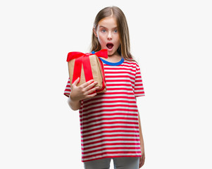 Young beautiful girl giving christmas or valentine gift over isolated background scared in shock with a surprise face, afraid and excited with fear expression