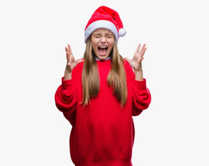 Young beautiful girl wearing christmas hat over isolated background celebrating mad and crazy for success with arms raised and closed eyes screaming excited. Winner concept
