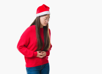 Young Chinese woman over isolated background wearing christmas hat with hand on stomach because indigestion, painful illness feeling unwell. Ache concept.