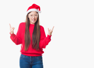 Fototapeta na wymiar Young Chinese woman over isolated background wearing christmas hat shouting with crazy expression doing rock symbol with hands up. Music star. Heavy concept.