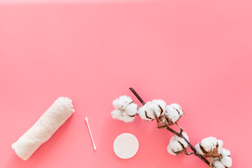 Cotton hygiene products. Cotton pads and swabs, towels twisted coil near dry cotton flowers on pink background top view space for text