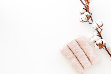 Spa concept. Set of towels twisted coil near cotton flowers on white background top view copy space