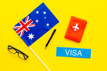 Visa to Australia concept. Text visa near passport cover and australian flag on yellow background top view