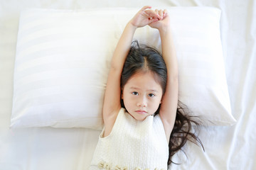 Portrait of beautiful Asian child girl lying on bed. View from above.