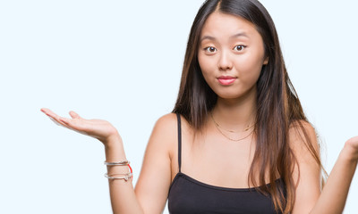 Young asian woman over isolated background clueless and confused expression with arms and hands...