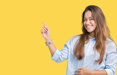 Young beautiful brunette business woman over isolated background with a big smile on face, pointing with hand and finger to the side looking at the camera.