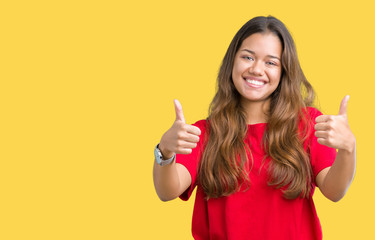 Young beautiful brunette woman wearing red t-shirt over isolated background success sign doing positive gesture with hand, thumbs up smiling and happy. Looking at the camera with cheerful expression