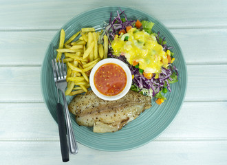 Fish grilled steak and French Fries in blue dish on white wood floor background props decoration with green salad, purple cauliflower, Top view,Copy Space..
