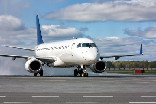 Fototapeta Taxiing a white passenger jet plane after passing through a water arch